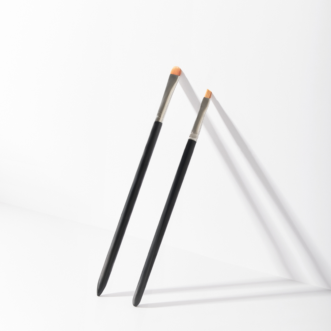 Set pennelli professionali PMU nero e argento, composto da pennello ovale grande e pennello angolato piccolo, ideali per trucco permanente, eyeliner, sopracciglia e correzioni di precisione.