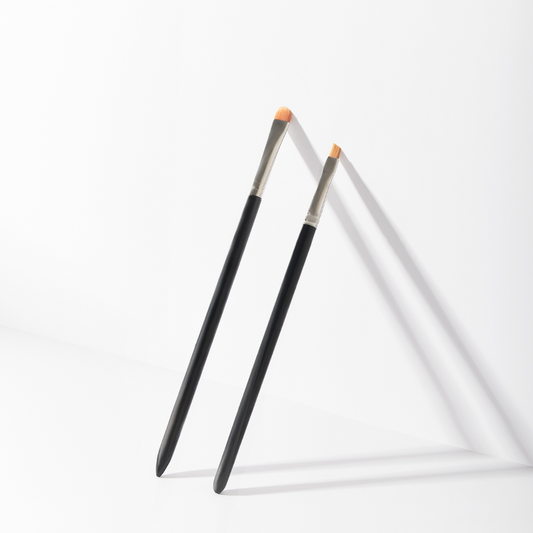 Set pennelli professionali PMU nero e argento, composto da pennello ovale grande e pennello angolato piccolo, ideali per trucco permanente, eyeliner, sopracciglia e correzioni di precisione.