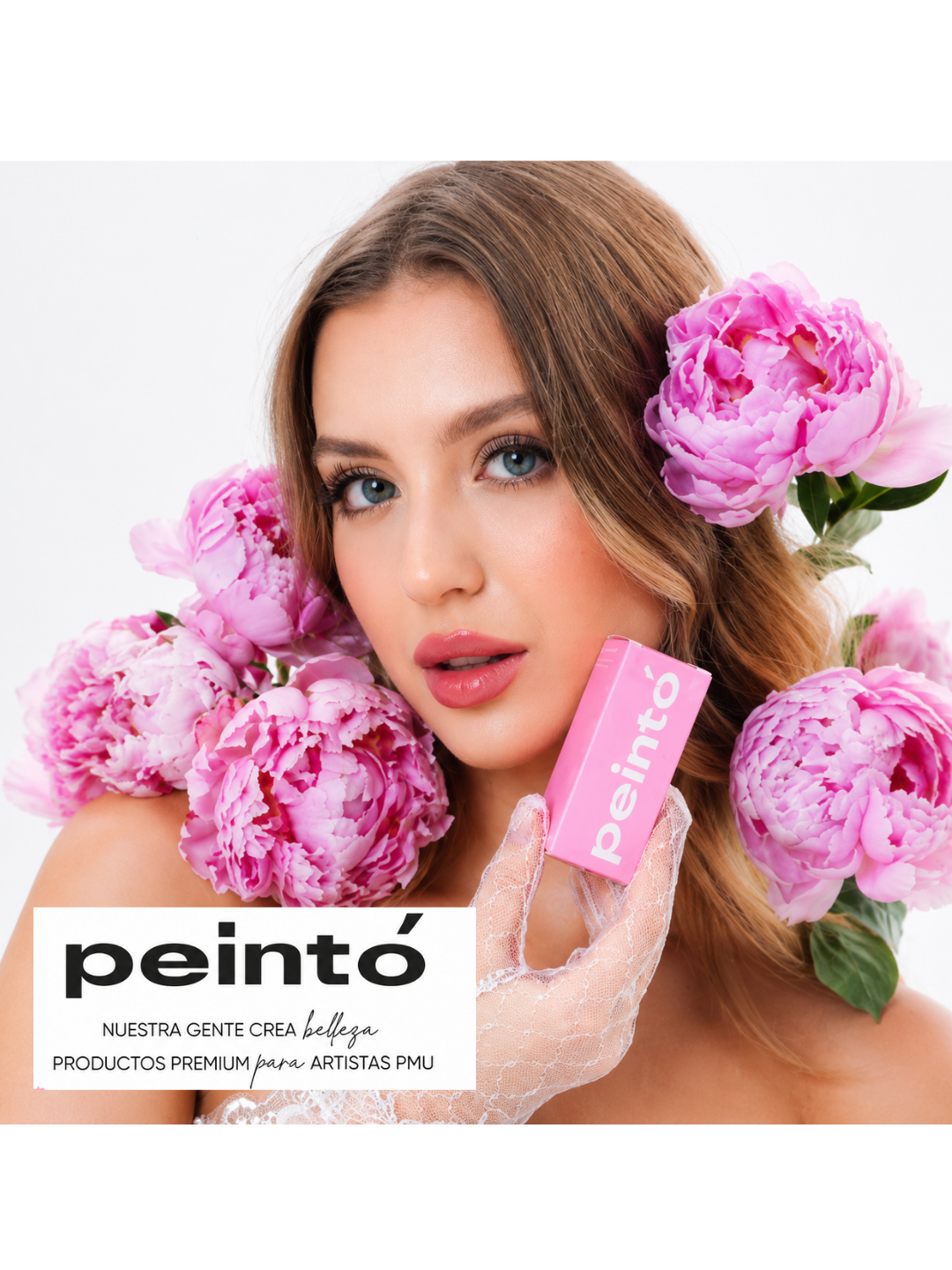 Modella Peintó circondata da fiori rosa mentre presenta una confezione di pigmenti per trucco permanente.